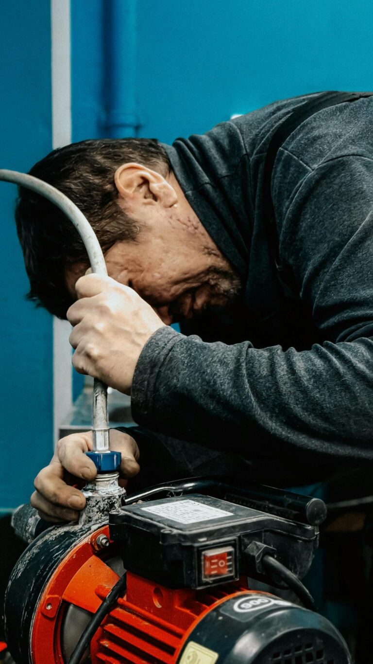 A technician concentrates on adjusting a water pump indoors.