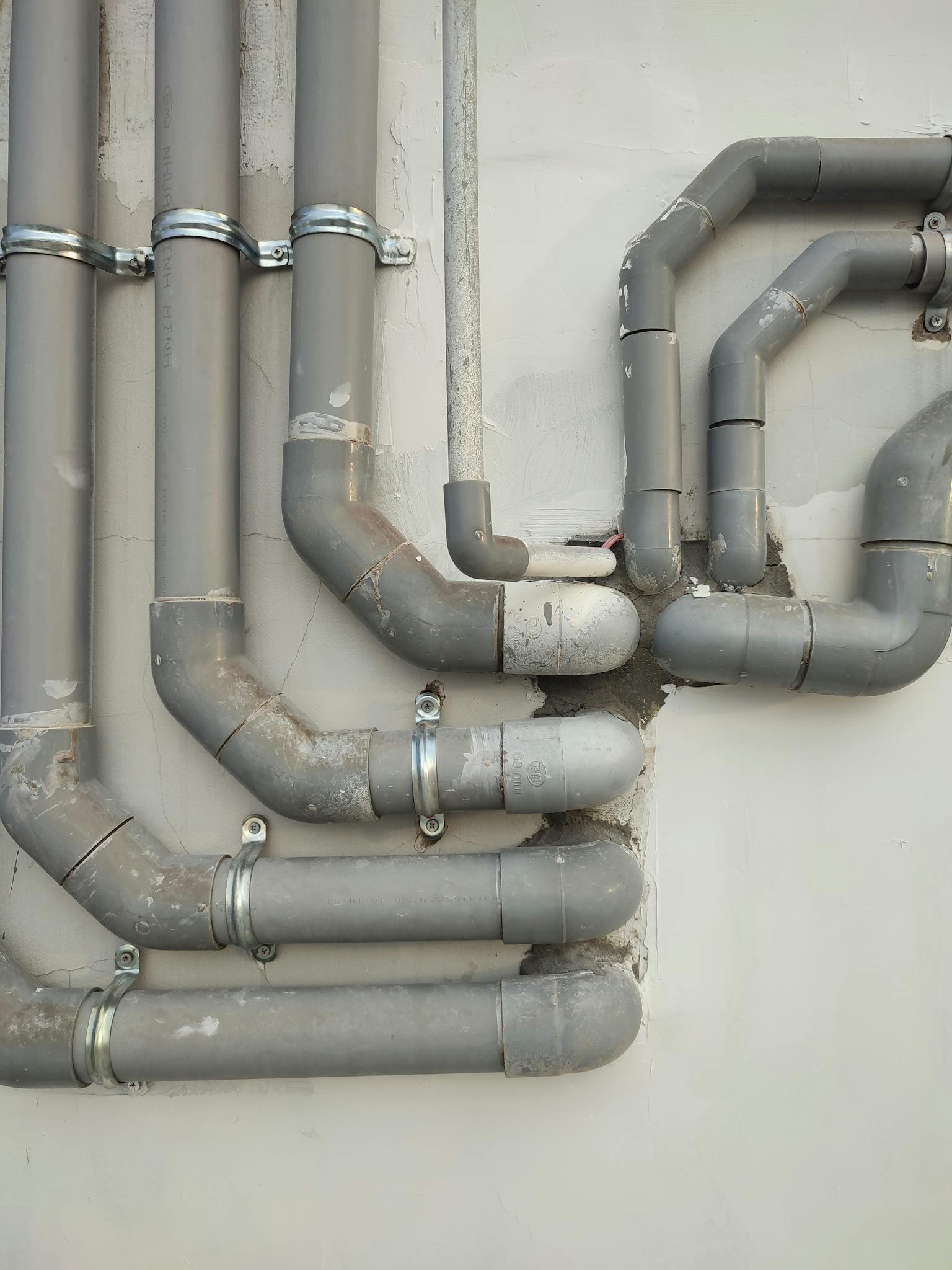 Close-up of interconnected gray metal pipes on an outdoor wall showcasing industrial design.